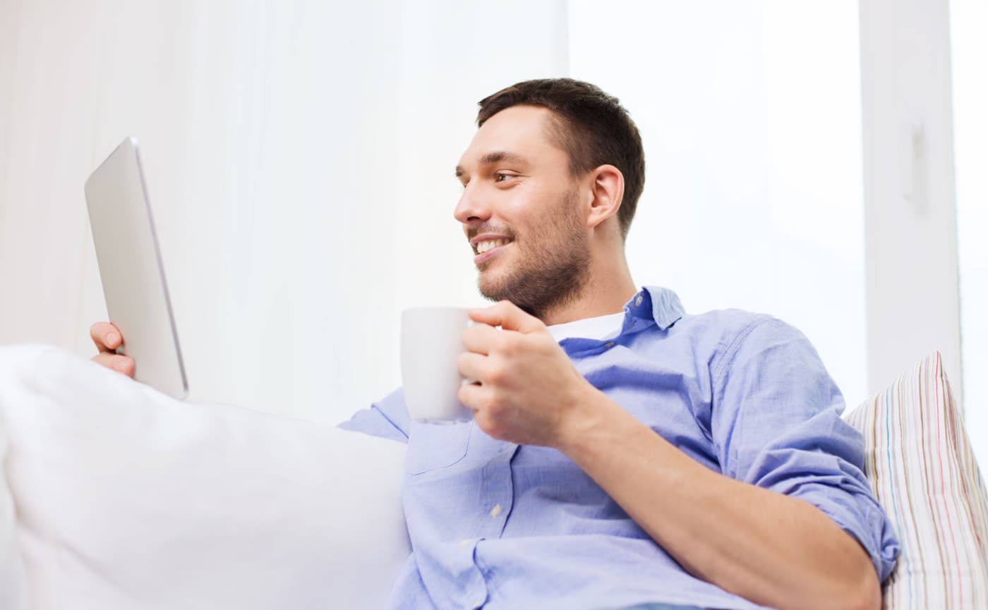 Man met tablet en koffie op de bank