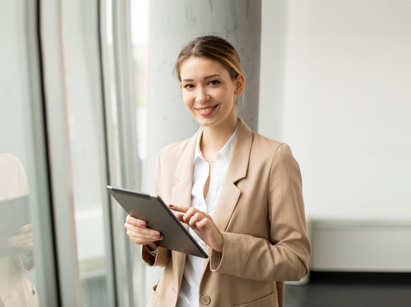 Medewerker met tablet bij een raam op kantoor